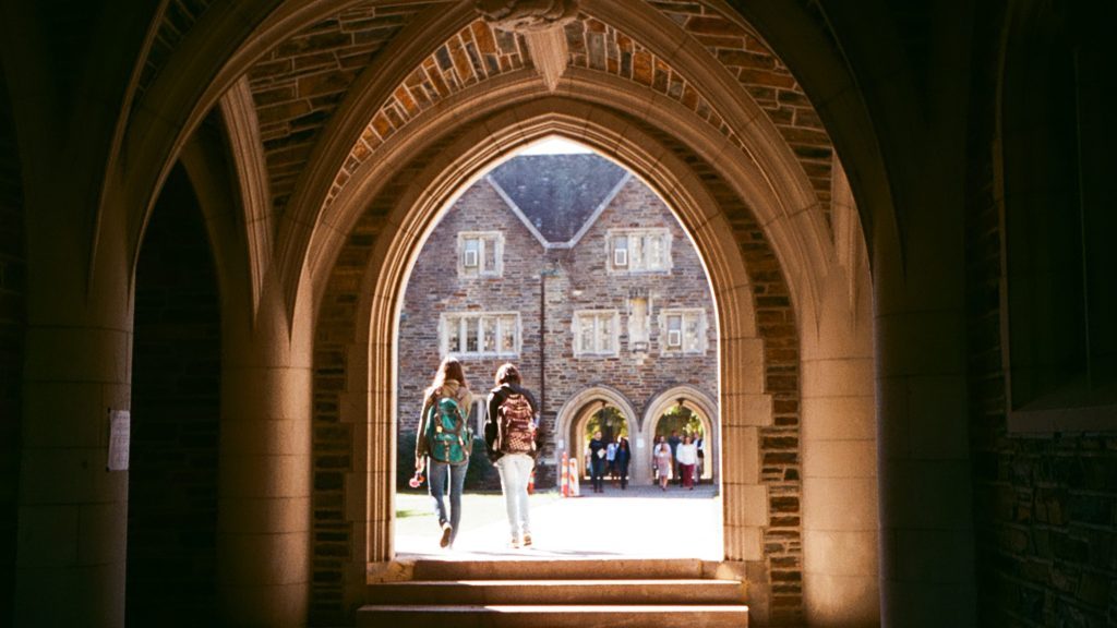 Students walking to class under archway on Duke campus